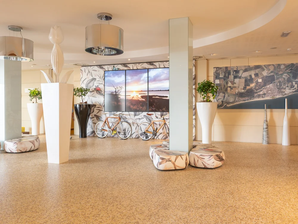 Bibione Palace Hotel · La tua casa al mare a 4 stelle S Interno moderno con piante, biciclette e grandi schermi a parete