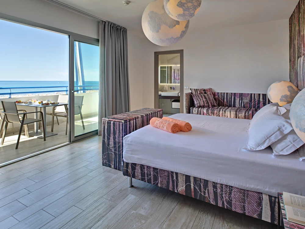 Bibione Palace Hotel · La tua casa al mare a 4 stelle S Camera d'albergo con letto, divano, balcone e vista mare