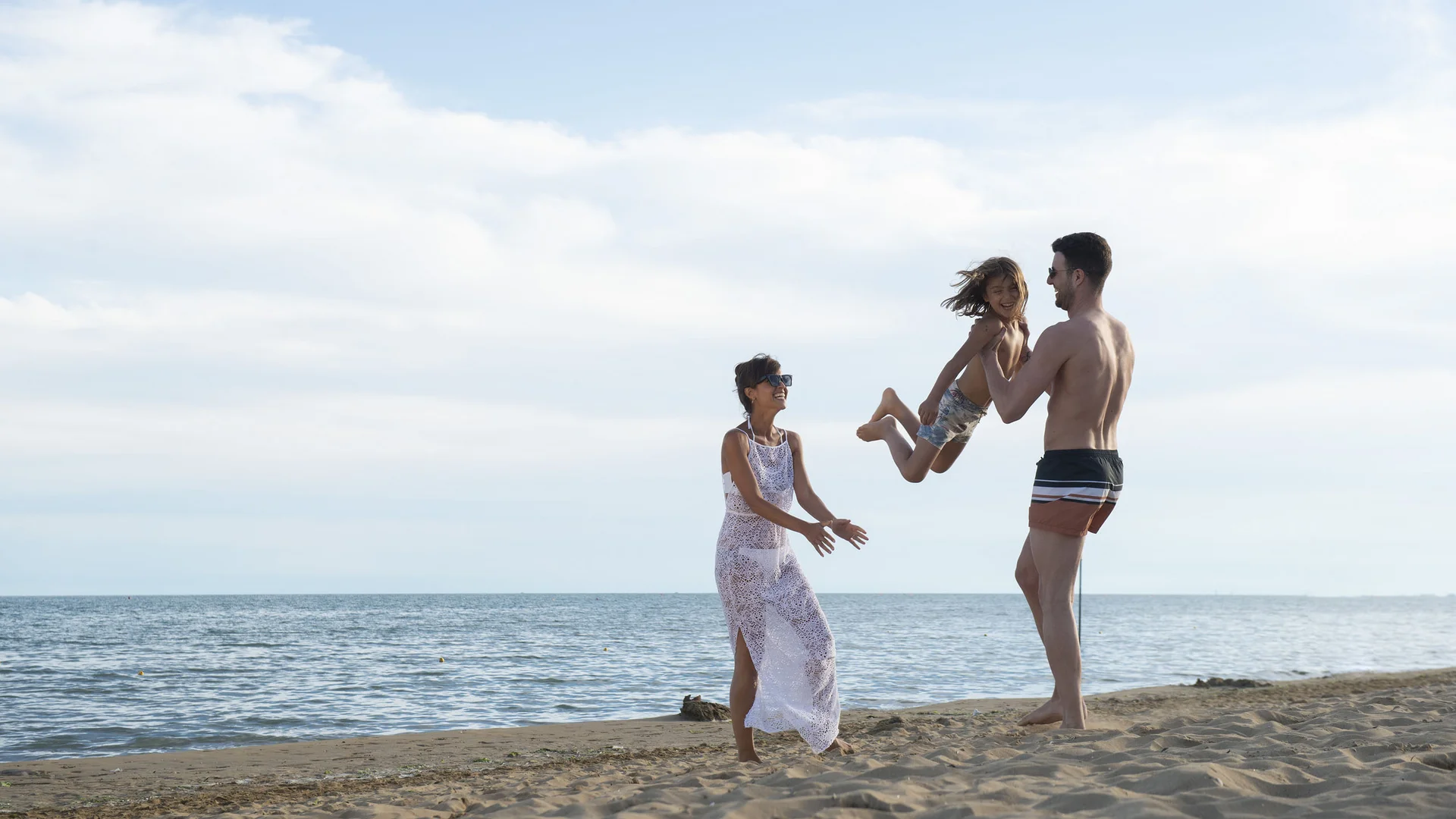 Famiglia felice che gioca sulla spiaggia vicino al mare