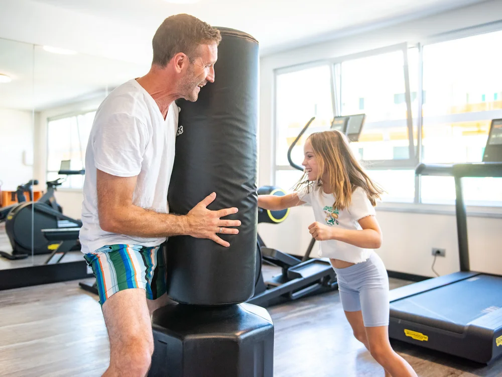 Bibione Palace Hotel · La tua casa al mare a 4 stelle S Uomo e bambina che si allenano con un sacco da boxe in palestra