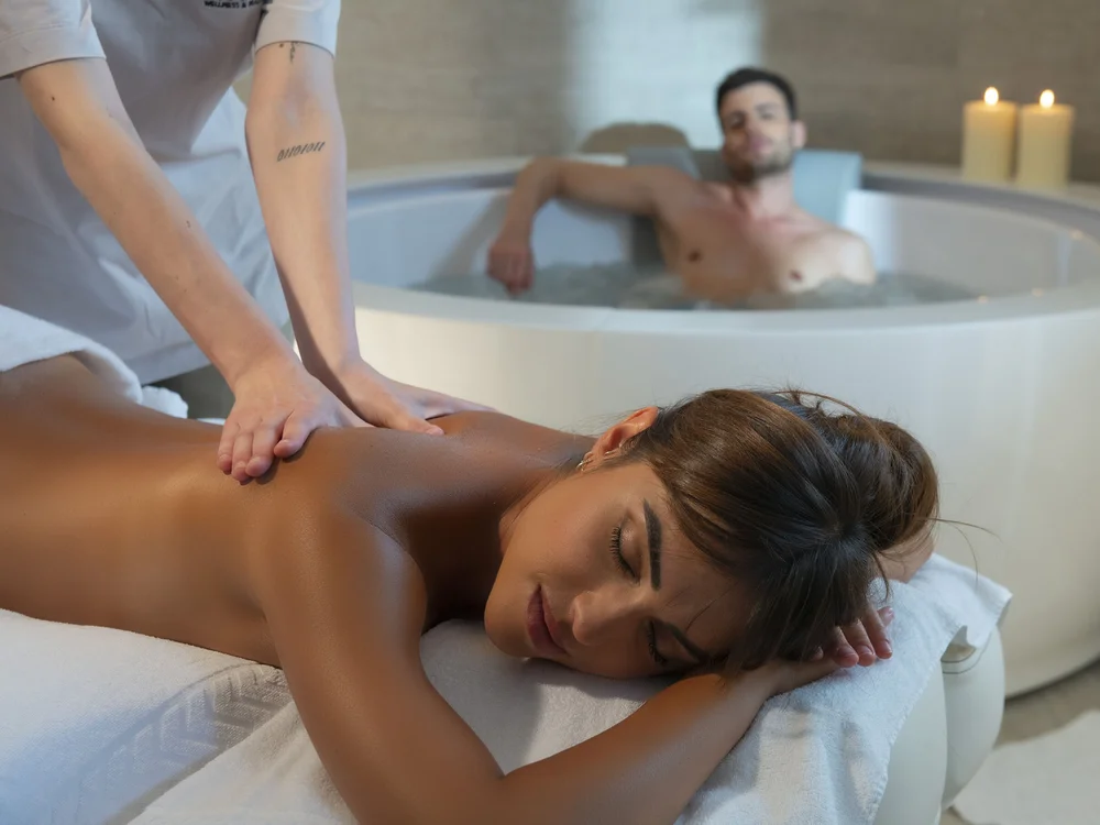 Bibione Palace Hotel · La tua casa al mare a 4 stelle S Donna che riceve un massaggio mentre un uomo si rilassa in una vasca idromassaggio
