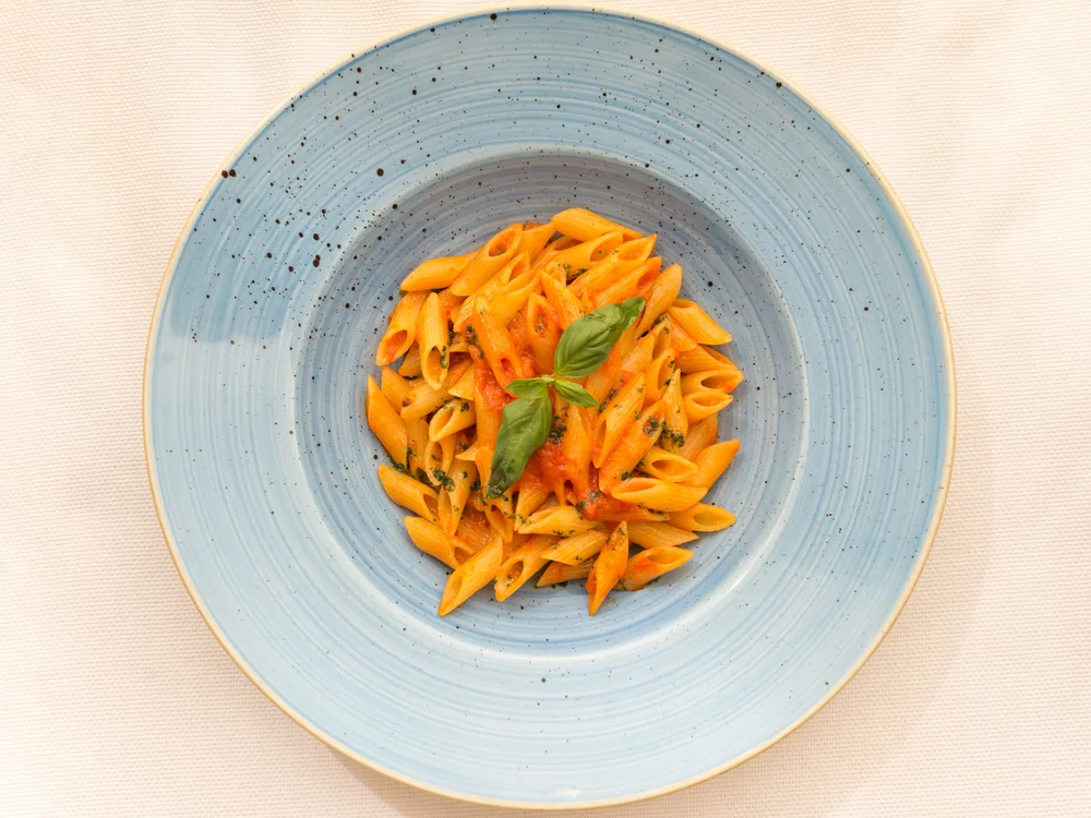 Bibione Palace Hotel · La tua casa al mare a 4 stelle S piatto di pasta penne con salsa di pomodoro e basilico su piatto azzurro