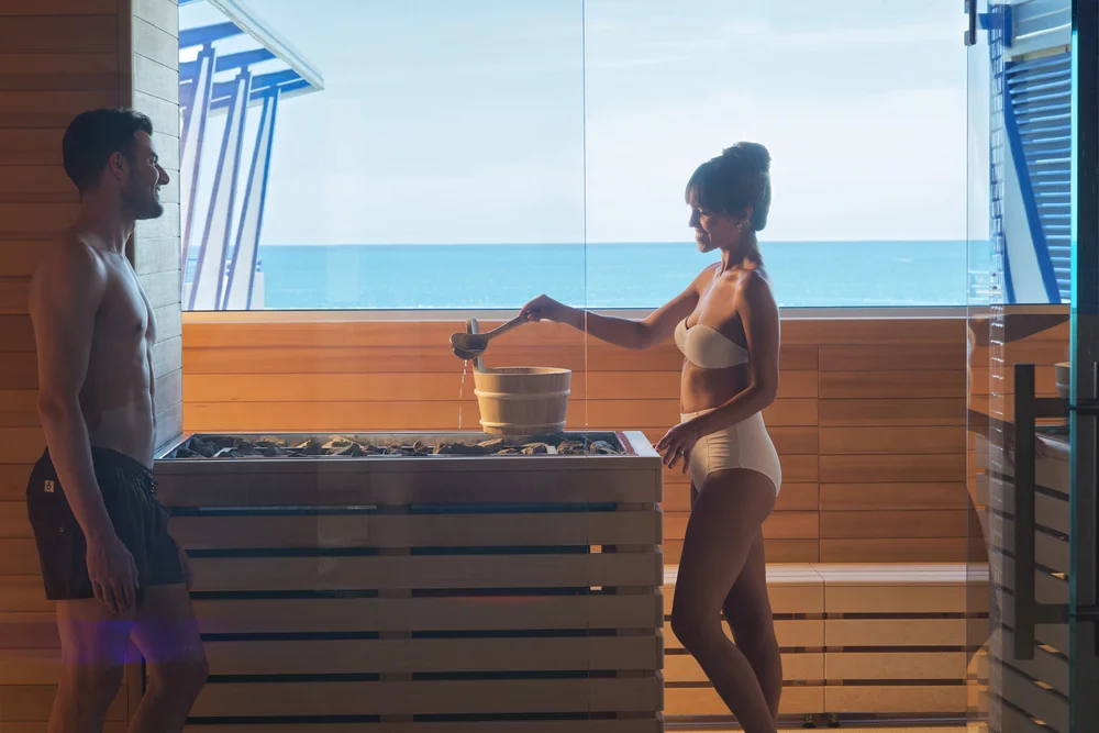 Coppia in costume da bagno nella sauna con vista sul mare