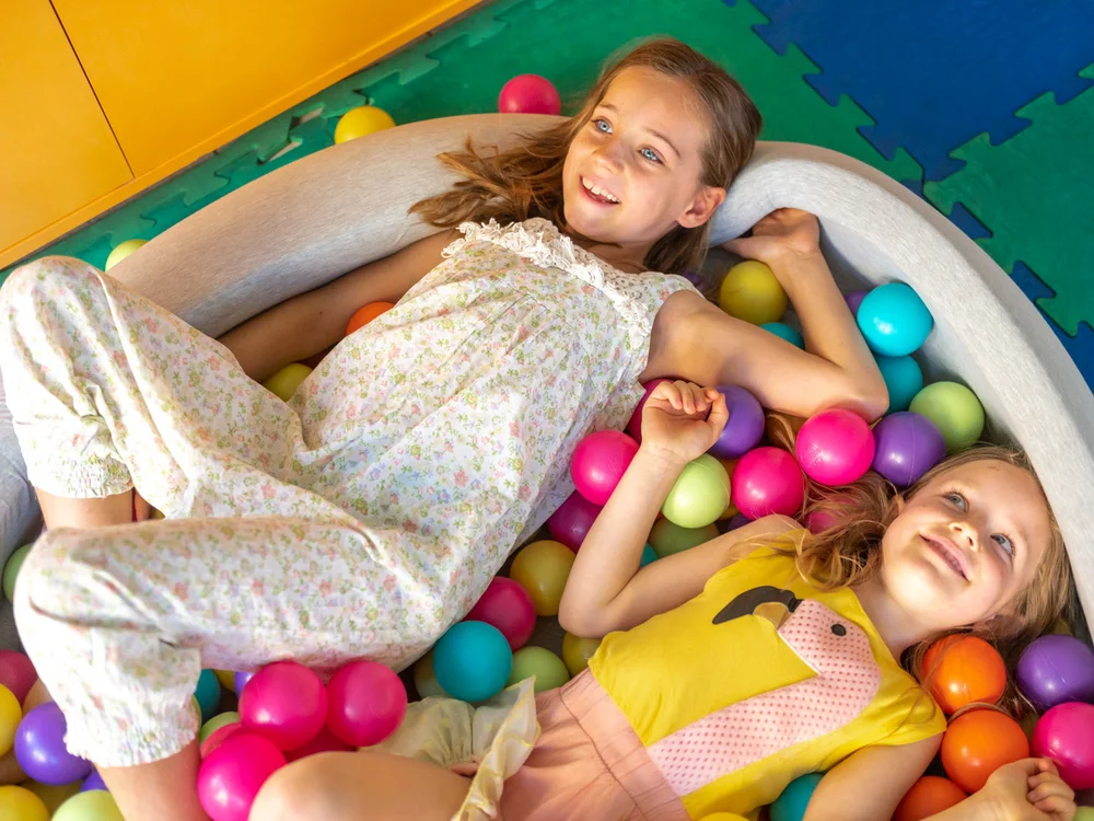 Bibione Palace Hotel · La tua casa al mare a 4 stelle S Due bambine sorridenti che giocano in una piscina di palline colorate