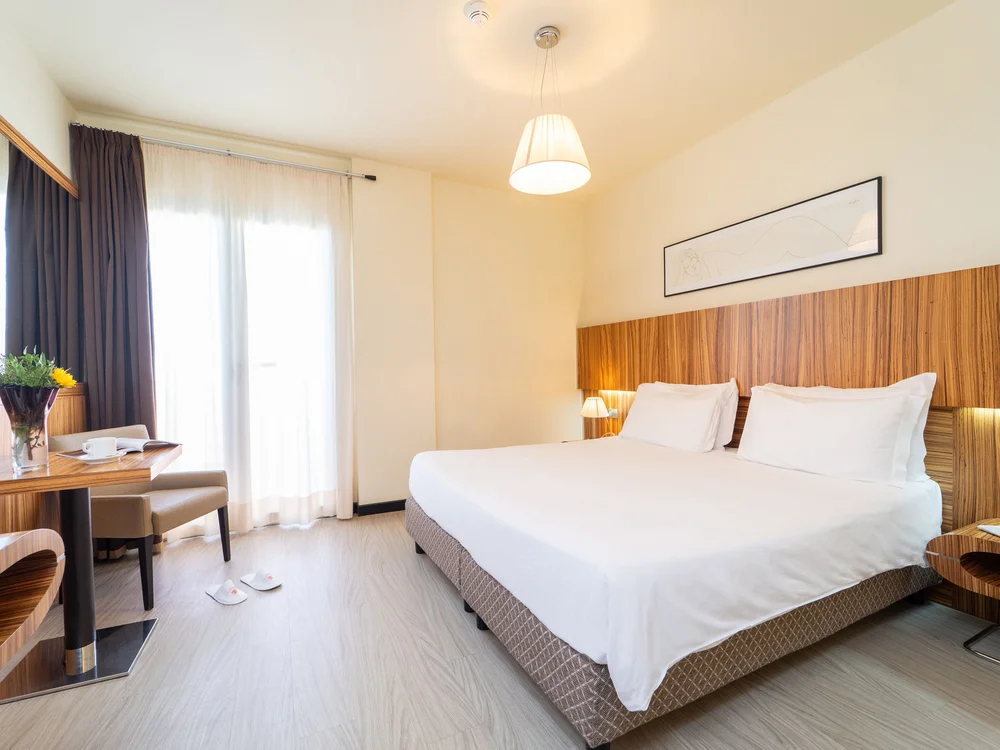 Bibione Palace Hotel · La tua casa al mare a 4 stelle S Camera d'albergo moderna con letto matrimoniale e scrivania in legno