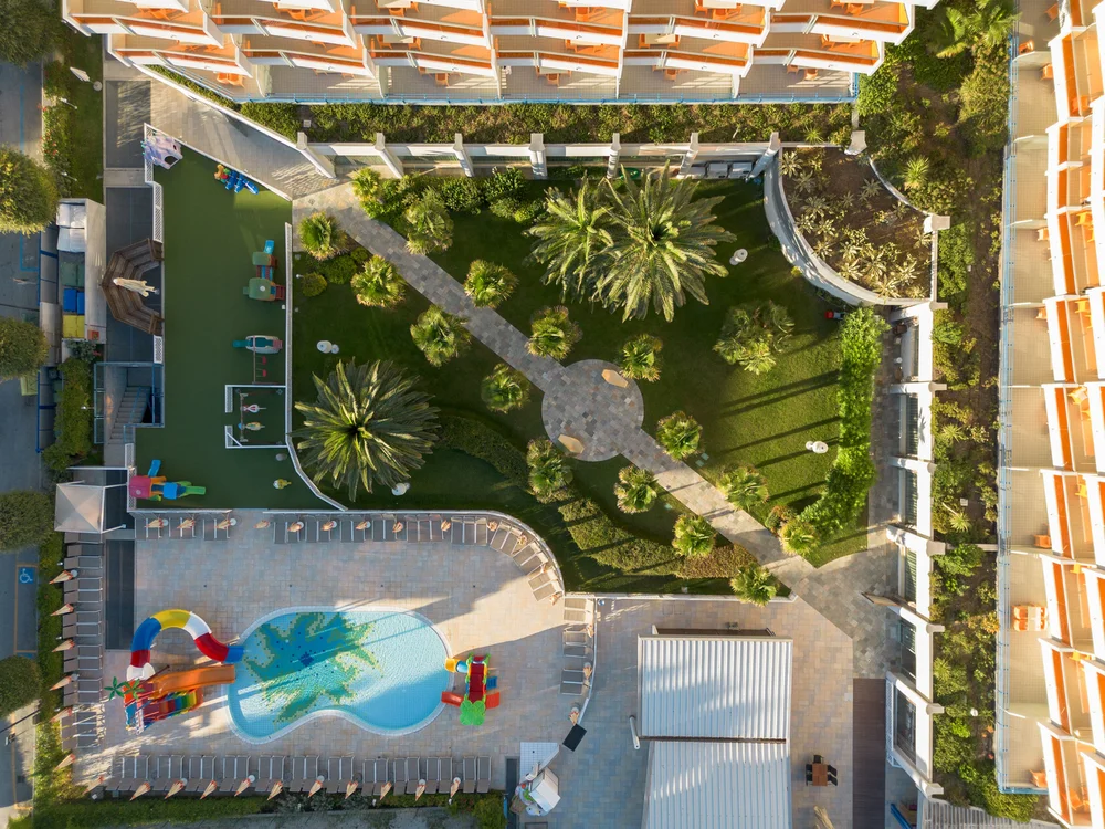Bibione Palace Hotel · La tua casa al mare a 4 stelle S Vista aerea di una piscina con scivoli e area giochi in un hotel con giardino
