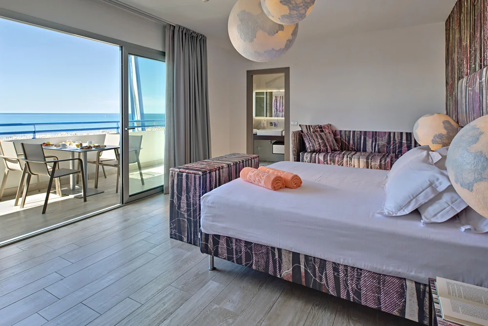 Camera d'albergo con letto, divano, balcone e vista mare