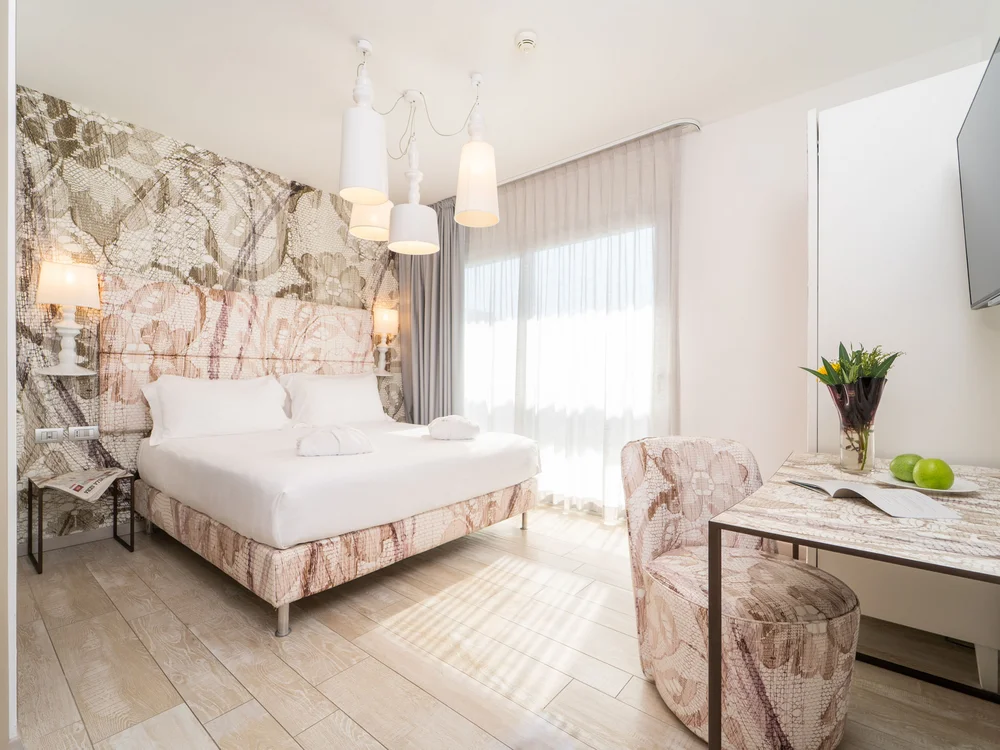 Bibione Palace Hotel · La tua casa al mare a 4 stelle S Camera d'albergo luminosa con letto matrimoniale e scrivania moderna
