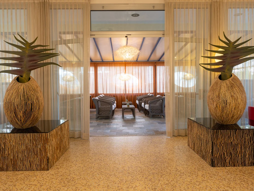 Bibione Palace Hotel · La tua casa al mare a 4 stelle S Ingresso con grandi vasi decorativi e area salotto con poltrone e tavolini