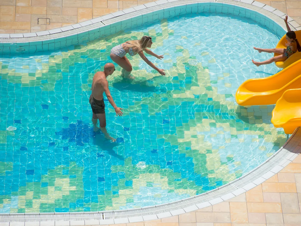 Bibione Palace Hotel · La tua casa al mare a 4 stelle S Famiglia che gioca in una piscina con scivolo giallo