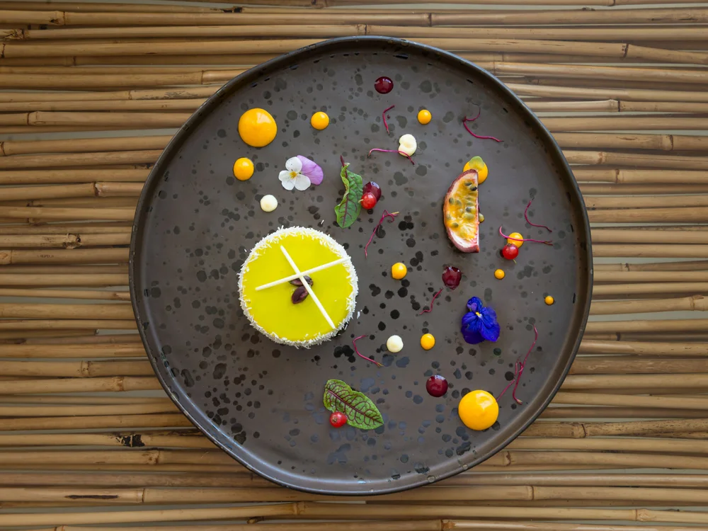 Bibione Palace Hotel · La tua casa al mare a 4 stelle S Dessert gourmet con decorazioni floreali e frutta su piatto nero