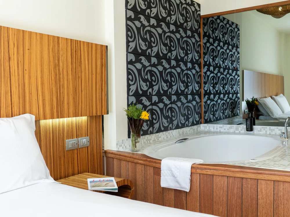 Bibione Palace Hotel · La tua casa al mare a 4 stelle S Camera d'hotel con letto e vasca da bagno adiacente con decorazioni a parete